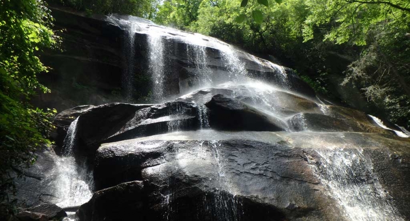 A waterfall streams over rocks framed by green trees